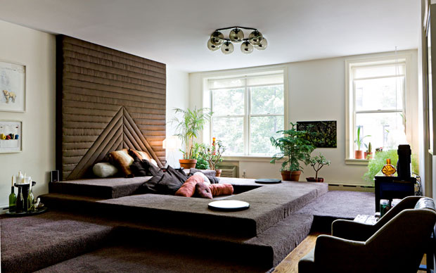Il living è un grande sofà conviviale fatto di piattaforme ricoperte di moquette marrone e da un muro imbottito di tessuto