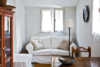 Il divano bianco e la credenza a vetri arredano l’ingresso-soggiorno- pranzo in uno stile tra classico e rustico; di provenienza Umbra le sedie. Collegata al soggiorno la cucina.