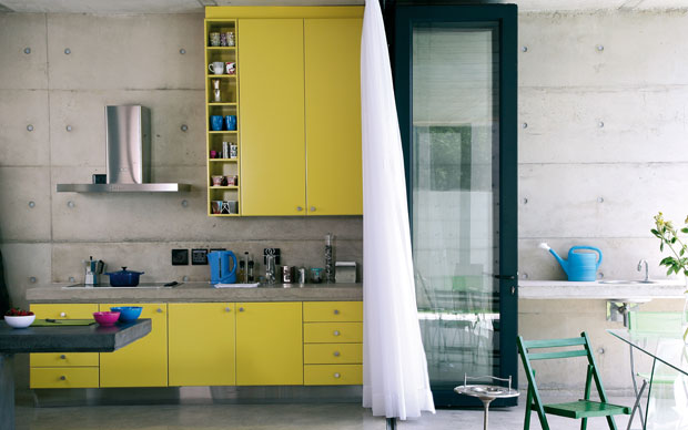 La cucina della casa di Johannesbourg: piano in cemento e mobili gialli