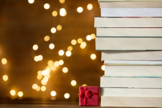 Christmas gift box and pile of books with fairy lights on background